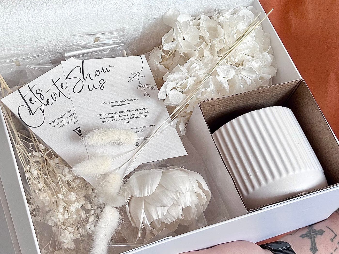 A packed kit held open, showing the vessel, stems and cards in one box